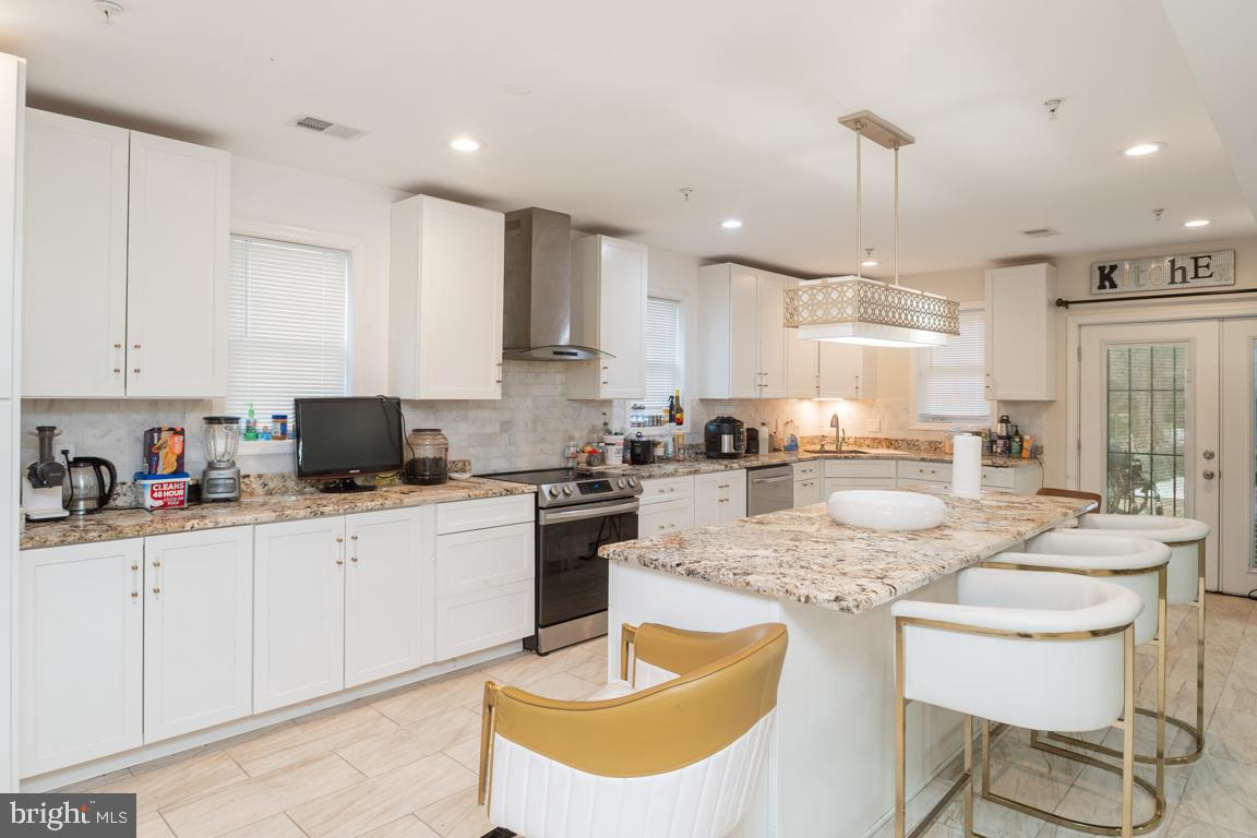 1710 Bargers Road Gambrills, MD 21054 - Photo 6 of 22 a kitchen with stainless steel appliances granite countertop a sink a stove a kitchen island with chairs and white cabinets