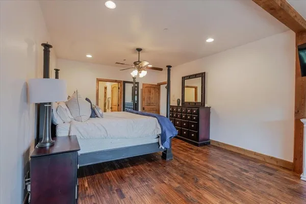 a spacious bedroom with a large bed a chandelier and dresser