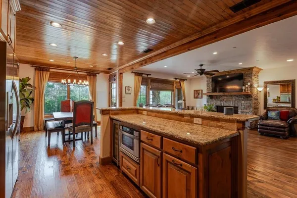 a kitchen with stainless steel appliances granite countertop a table chairs and a wooden floor