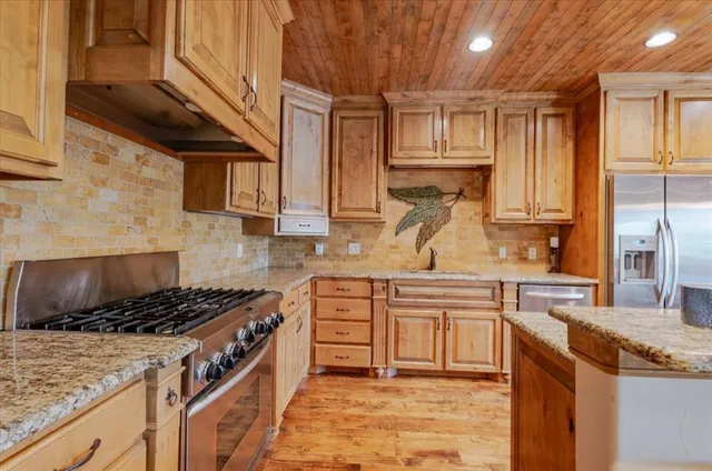 a kitchen with kitchen island granite countertop a sink cabinets and stainless steel appliances