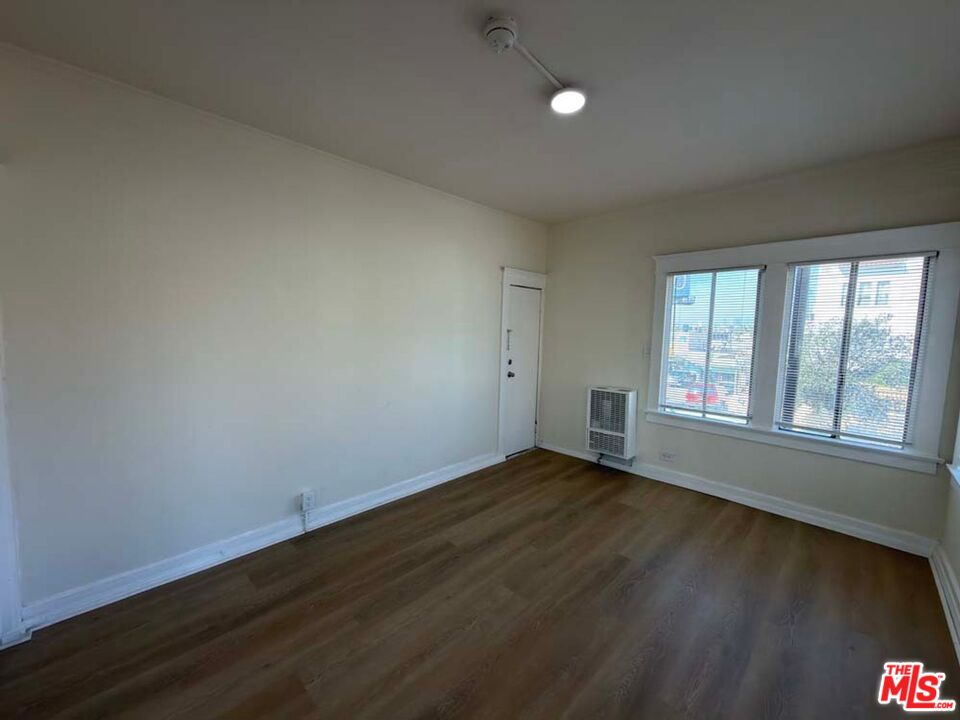 1298 Queen Anne Place, Unit 1 Los Angeles, CA 90019 - Photo 3 of 10 a view of an empty room with wooden floor and a window