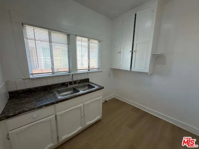 a kitchen with granite countertop cabinets a sink a window and a wooden floor
