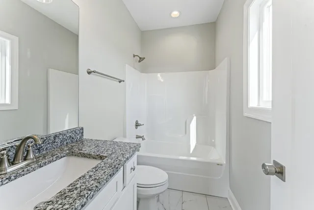 a bathroom with a granite countertop sink a toilet and shower