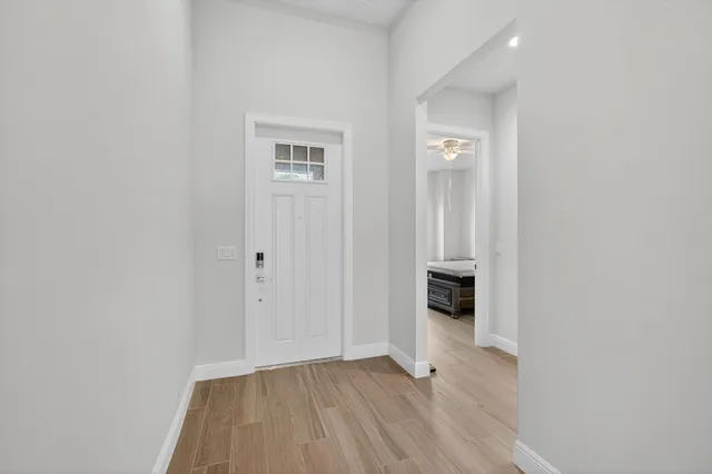 a view of a hallway with wooden floor and a bathroom