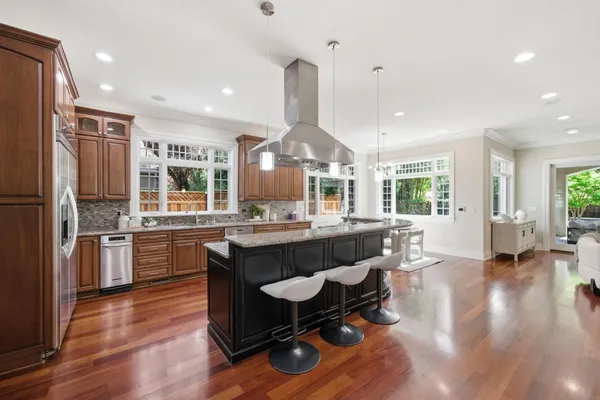 a kitchen with stainless steel appliances granite countertop hardwood floor sink stove and wooden cabinets