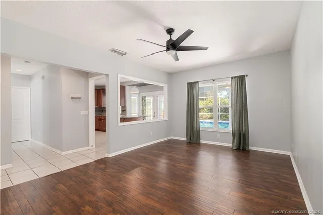 a view of an empty room with window and wooden floor