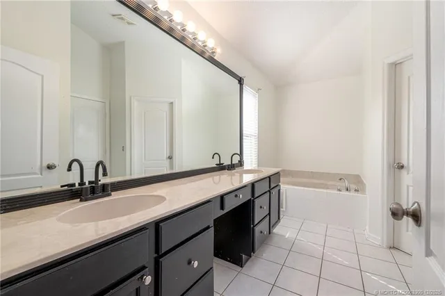 a bathroom with a double vanity sink a mirror and bathtub