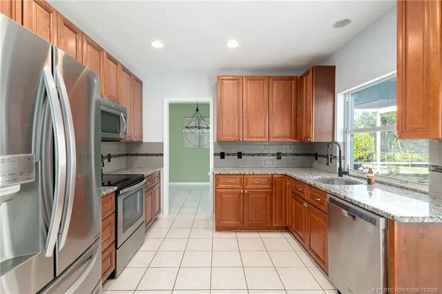 a kitchen with stainless steel appliances granite countertop a refrigerator a sink a stove a washer dryer and a cabinets