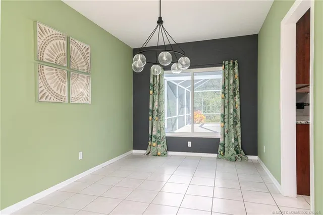 a view of an empty room with window and chandelier