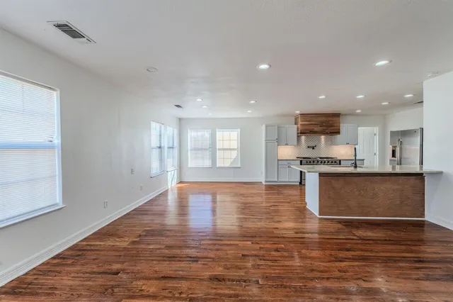 a view of kitchen with kitchen island granite countertop a stove top oven a sink and white cabinets with wooden floor