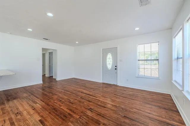 a view of an empty room with wooden floor and window