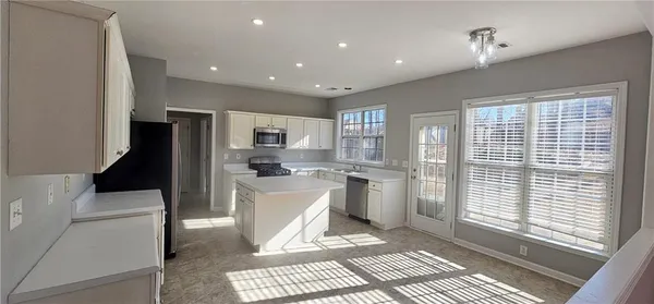 a living room with stainless steel appliances furniture a rug and a window