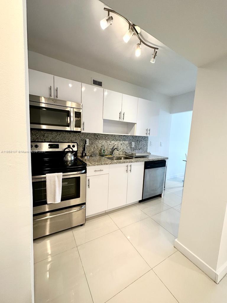 100 Lincoln Road, Unit 1406 Miami Beach, FL 33139 - Photo 7 of 14 a kitchen with a stove a sink and a refrigerator