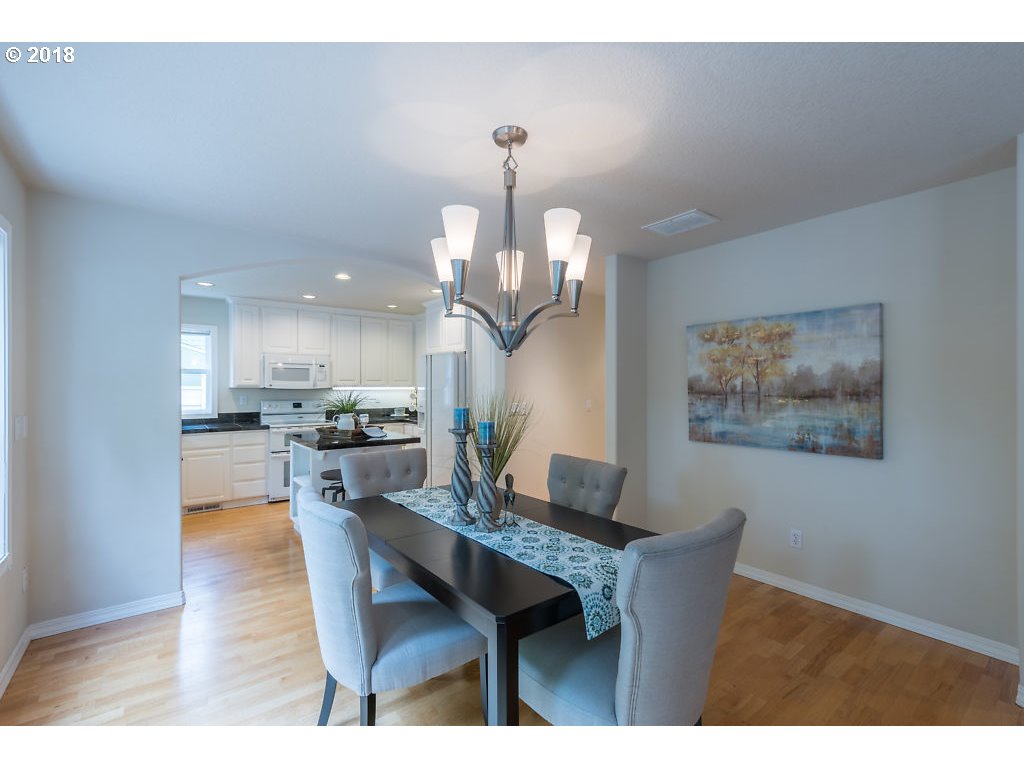 7571 Southwest Mapleleaf Street Portland, OR 97223 - Photo 12 of 32 a dining room with wooden floor a chandelier a wooden table and chairs