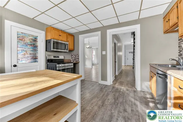 a open kitchen with kitchen island granite countertop wooden cabinets a sink a stove a refrigerator and a fireplace