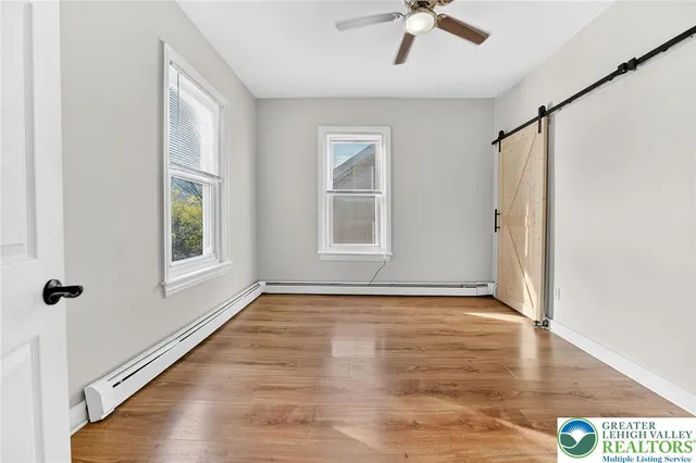 a view of an empty room with a window and wooden floor
