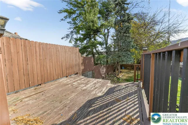 a view of backyard with wooden fence and large trees