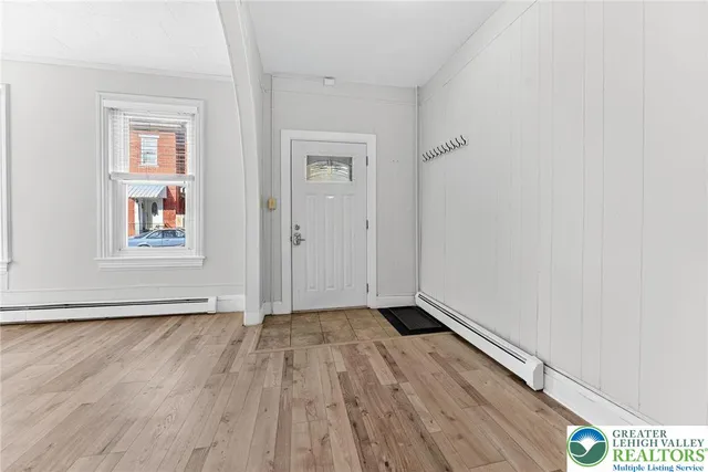 an empty room with wooden floor closet and windows