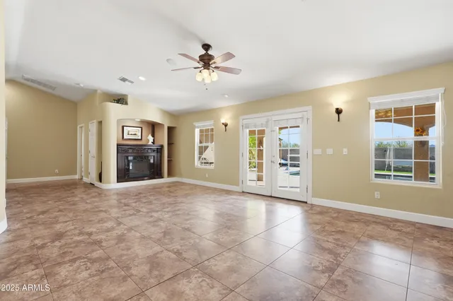 a view of an empty room with kitchen and chandelier