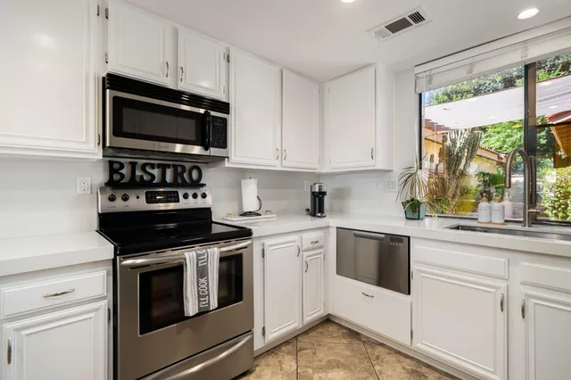 a kitchen with stainless steel appliances white cabinets and a stove top oven