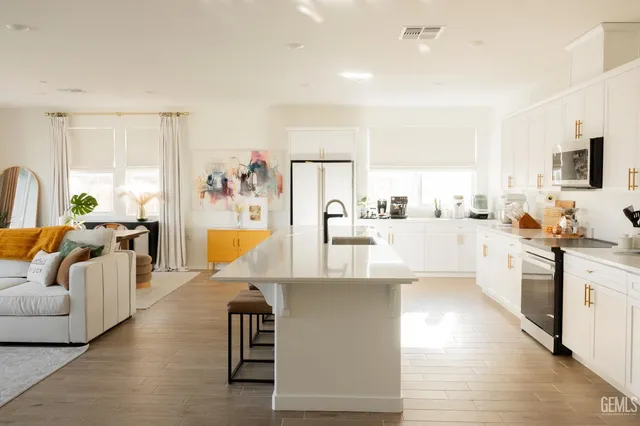 a living room with stainless steel appliances furniture a rug and a kitchen view