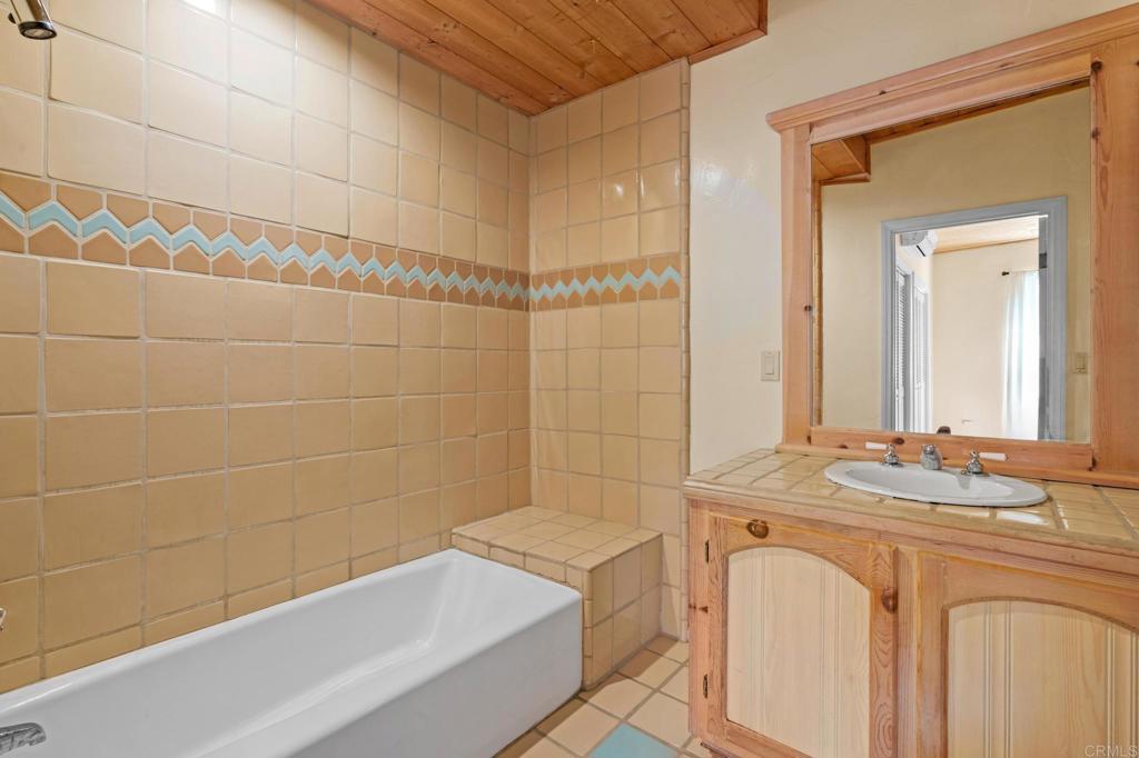 13511 Hilldale Road Valley Center, CA 92082 - Photo 41 of 46 a bathroom with a granite countertop sink a mirror and a bathtub