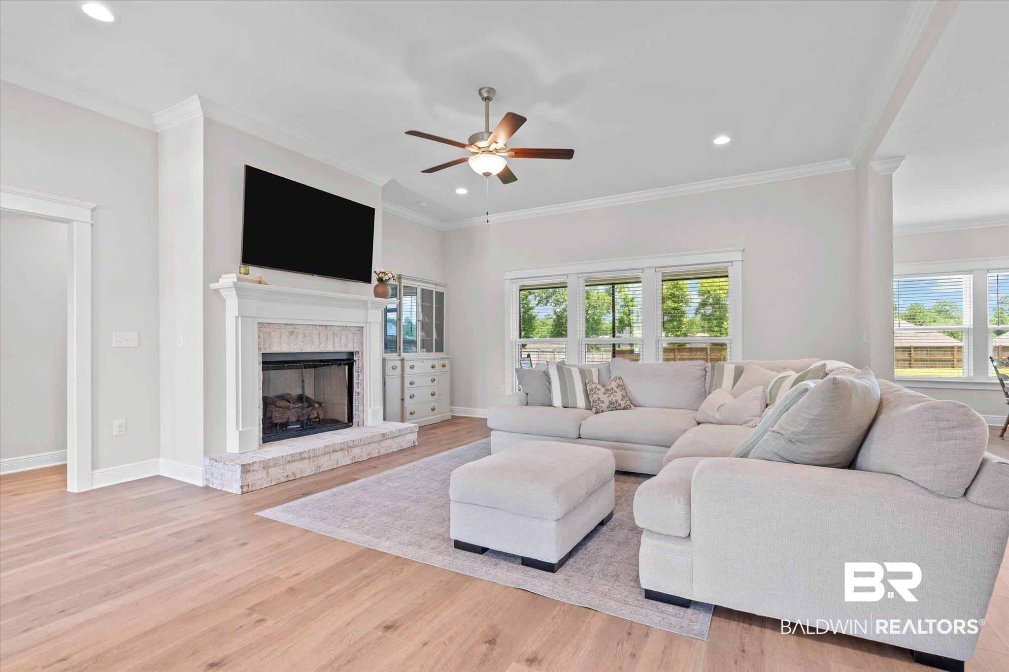 23523 Travis Stock Street Foley, AL 36535 - Photo 6 of 45 Spacious living area featuring light wood-finish flooring, a contemporary fireplace with a stone surround and hearth, recessed lighting, and a ceiling fan