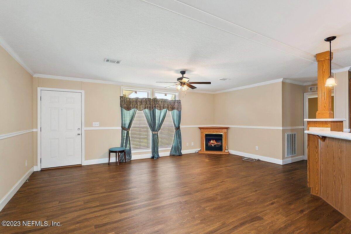 3823 Rancho Road Jacksonville, FL 32221 - Photo 4 of 17 an empty room with wooden floor fireplace and windows