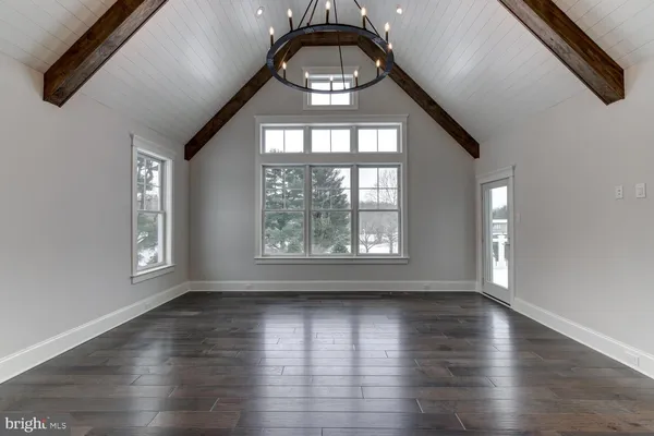 an empty room with wooden floor windows and entrance