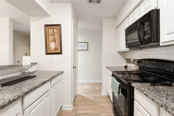 a kitchen with stainless steel appliances granite countertop a stove top oven microwave and refrigerator