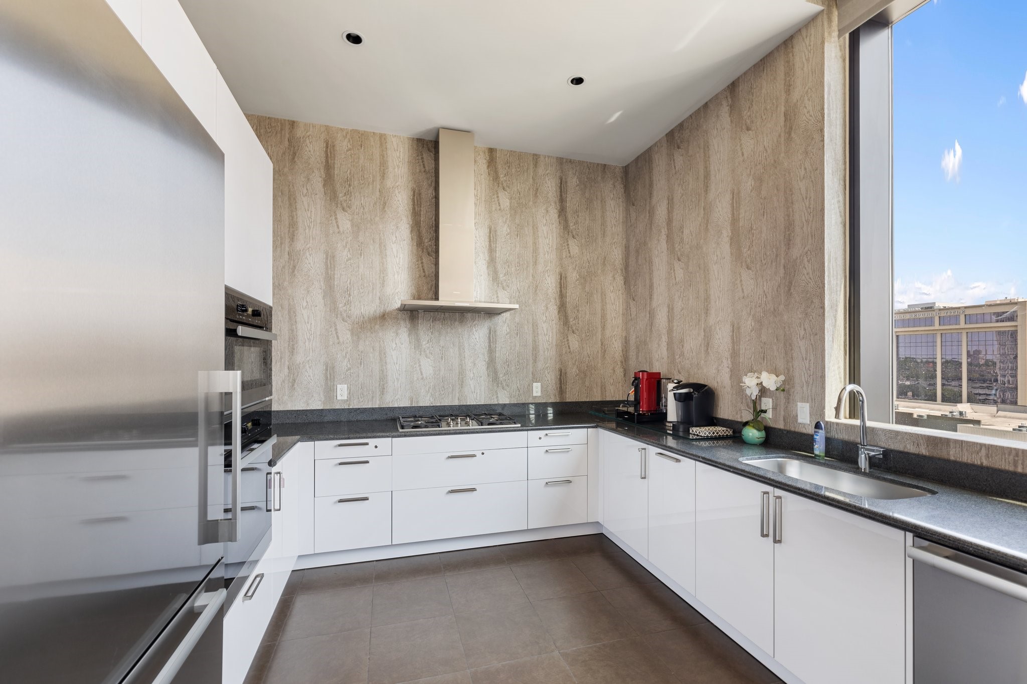 1409 Post Oak Boulevard, Unit 2702 Houston, TX 77056 - Photo 42 of 43 a kitchen with granite countertop a sink a stove and cabinets