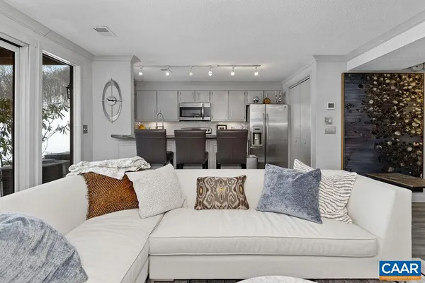 a living room with furniture a large window and stainless steel appliances