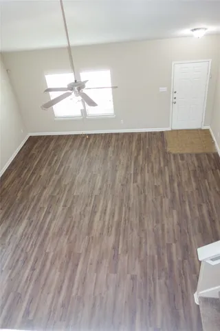 a view of a room with wooden floor and a ceiling fan