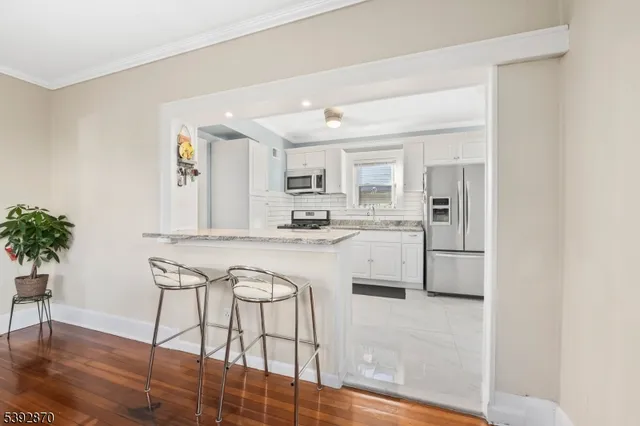 a kitchen with granite countertop white cabinets and stainless steel appliances