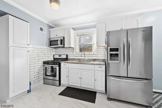 a kitchen with stainless steel appliances white cabinets and a refrigerator
