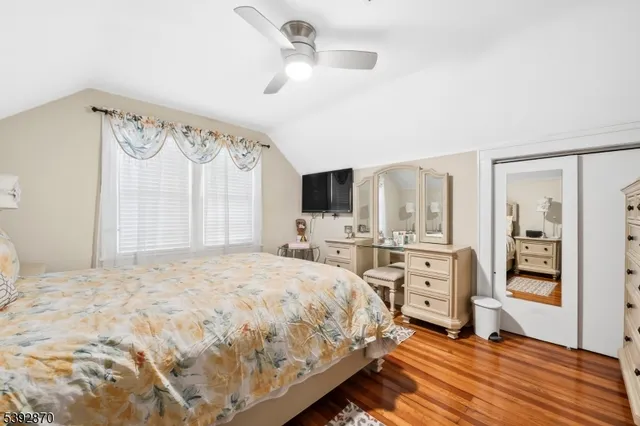 a bedroom with a large bed a flat tv screen and a dresser