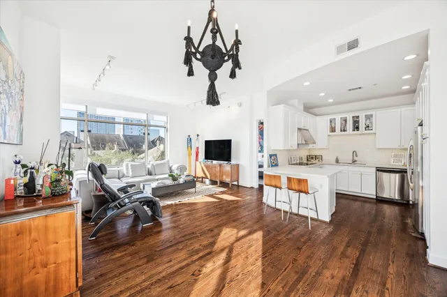 a living room with stainless steel appliances kitchen island granite countertop furniture and a wooden floor