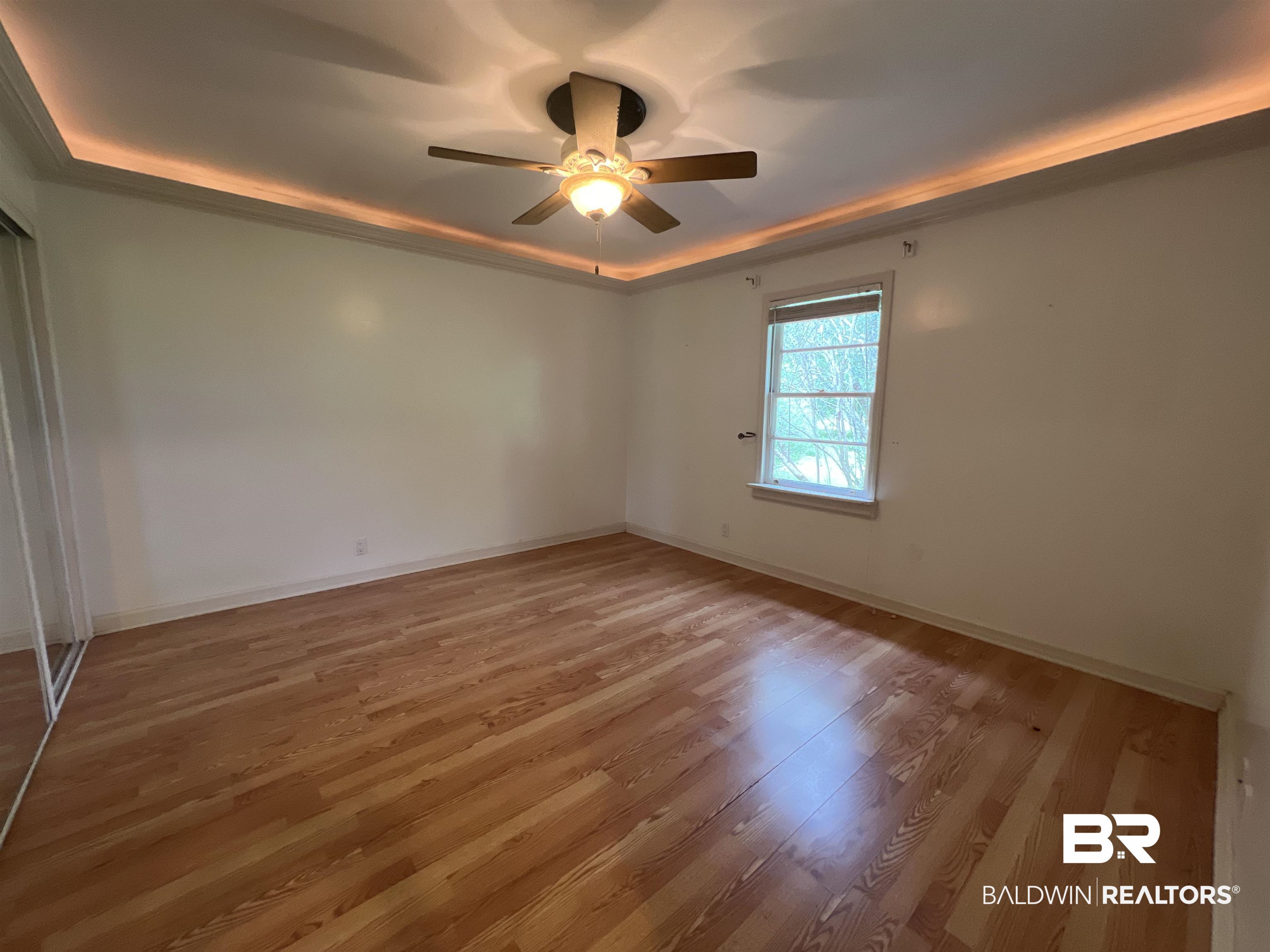 13301 A Hugh Fort Road Grand Bay, AL 36541 - Photo 10 of 34 Spare room featuring a tray ceiling, light wood-type flooring, ceiling fan, and baseboards