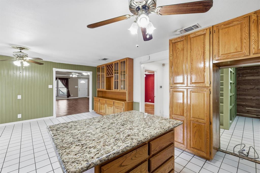 123 Valley Ranch Road Sherman, TX 75092 - Photo 8 of 40 Kitchen featuring a kitchen island, wood finish cabinets, light tile patterned floors, and wood walls