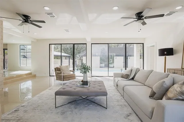 a living room with furniture ceiling fan and a large window