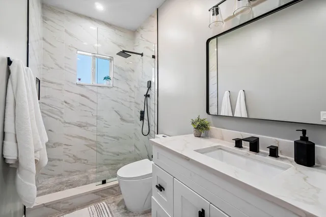 a bathroom with a granite countertop sink a toilet and shower