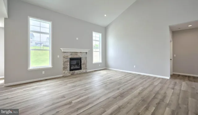 an empty room with wooden floor fireplace and windows