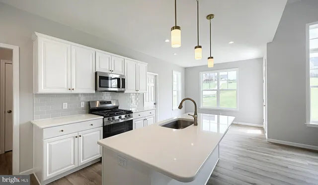 a kitchen with sink a stove and white cabinets with wooden floor