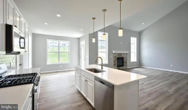 a kitchen with granite countertop a sink a counter top space stainless steel appliances and a window