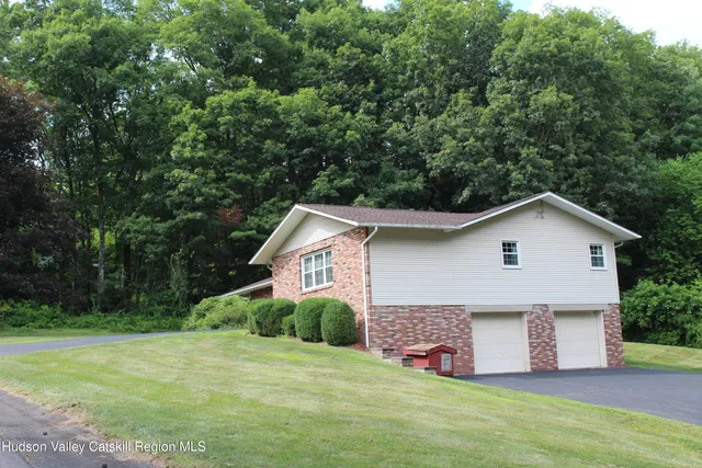 a front view of house with yard and trees in the background