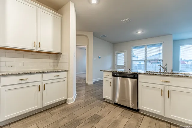a kitchen with stainless steel appliances granite countertop a stove a sink and white cabinets