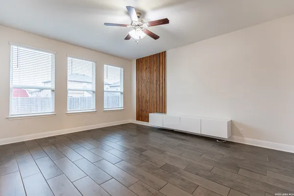 a view of an empty room with a window and wooden floor
