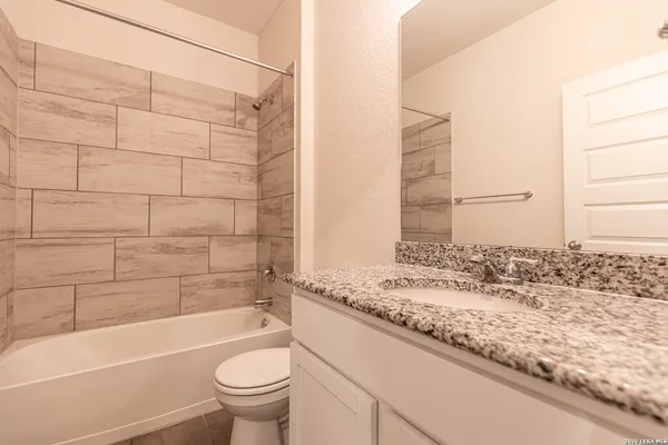 a bathroom with a granite countertop sink a toilet and bathtub