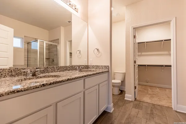 a bathroom with a granite countertop sink mirror and a toilet