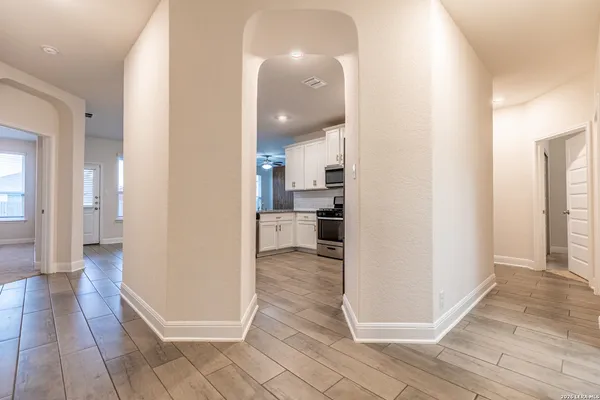 a view of a hallway with wooden floor kitchen and living room